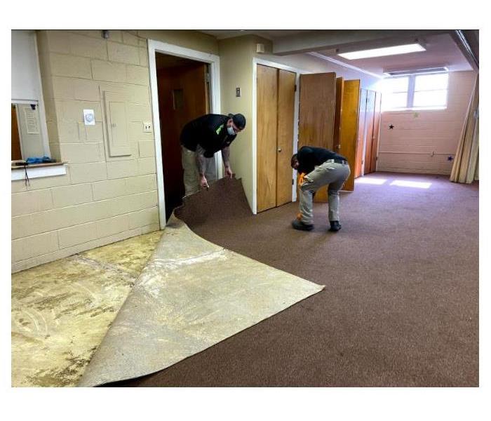 SERVPRO employees removing a carpet.